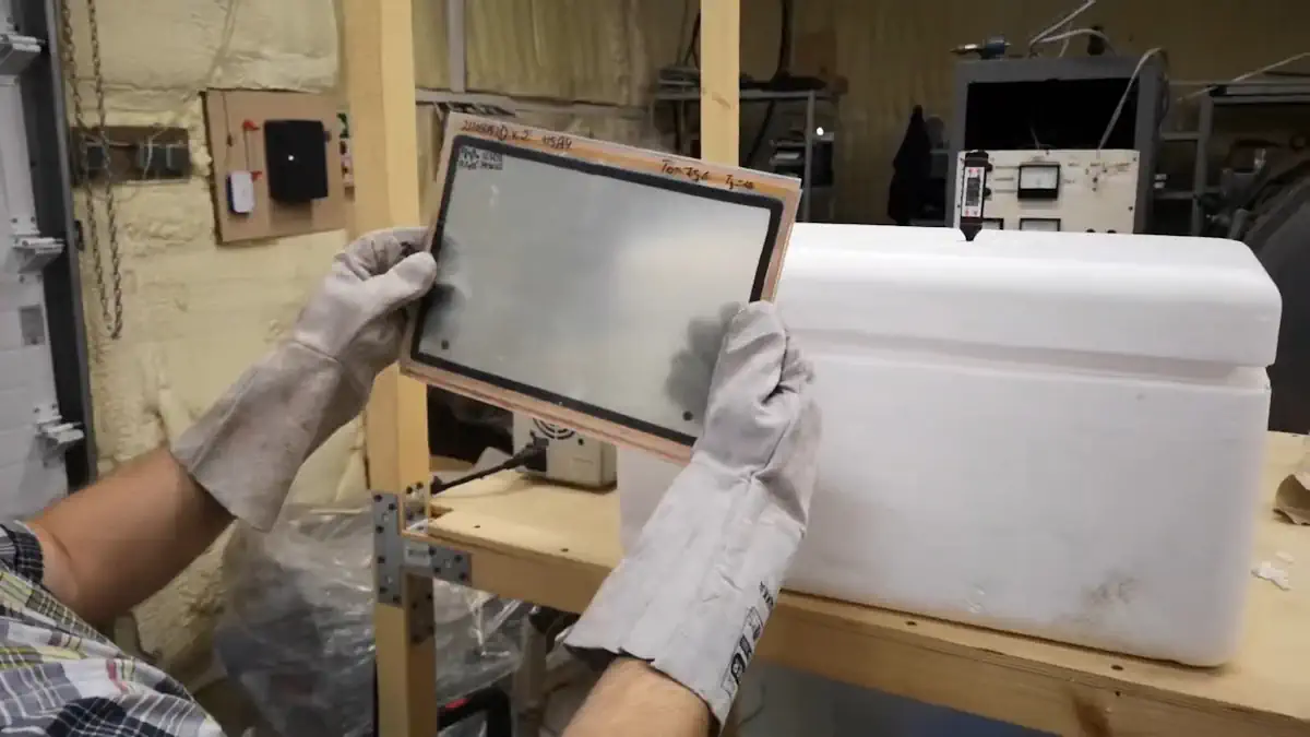 Holding the frozen glass sample in insulated gloves
